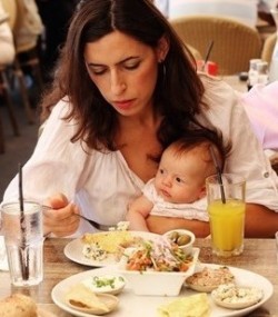 Mutter isst mit Baby auf dem Schoss