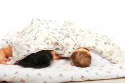 Mutter und Baby schlafen unter einer Bettdecke