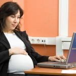 Schwangere Frau sitzt vor ihrem Laptop