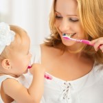 Mutter und Baby üben gemeinsam das Zähneputzen