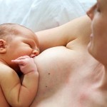 Mutter stillt ihr Baby Haut an Hautin zurückgelehnten Position