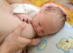 Die Mutter stützt mit ihrer Hand die Brust im C-Griff.