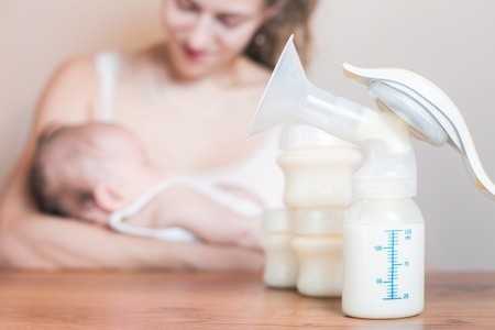 Mutter füttert ihr Baby mit abgepumpter Muttermilch