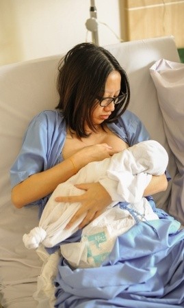 Mutter im Krankenhaus versucht ihr Baby zum Stillen anzulegen