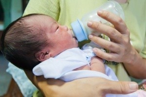Chinesisches Mutter füttert ihr Baby mit der Flasche