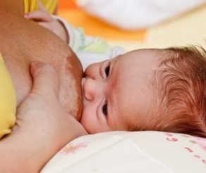 Mutter drückt ihre Brust beim Stillen zusammen.