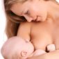 Mutter stillt ihr Baby und lächelt sie an.