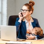 Mutter stillt vor dem Computer und mit Telefon in der Hand