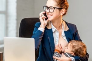 Mutter stillt vor dem Computer und mit Telefon in der Hand