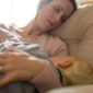Erschöpfte Mutter mit Kleinkind an der Brust