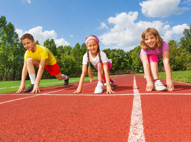 Drei kinder hocken in der Startposition zum Sprinten