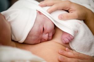 Neugeborenes liegt in einem Babyfreundlichen Krankenhaus auf der Brust der Mutter in Haut-zu-Haut-Kontakt
