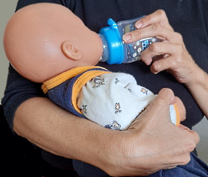 Frau füttert Baby mit Flasche, sie hält die Flasche flach