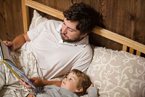 Vater liest seinem kleinen Sohn im Bett ein Buch vor.