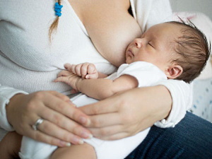 Baby schläft an der nackten Brust seiner stillenden Mutter