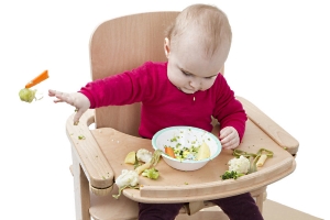 Kleinkind sitzt vor einem Teller voller Gemüse